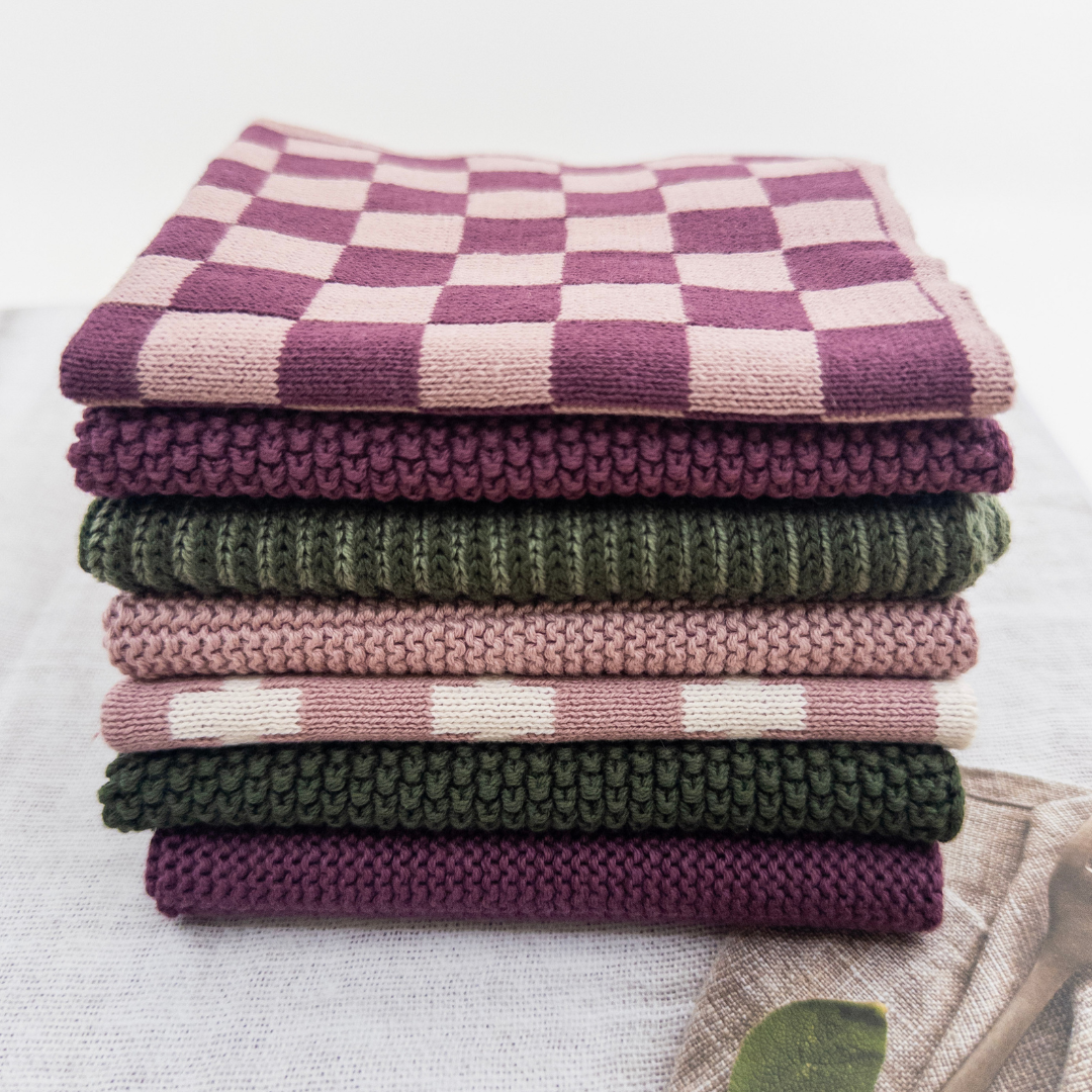 Stack of folded checkered and solid color cloths on a white background